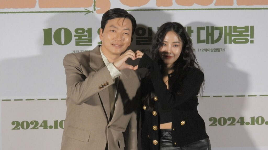 배우 이동휘와 한지은이 서로 손을 맞대 하트를 만들어 보이고 있다.